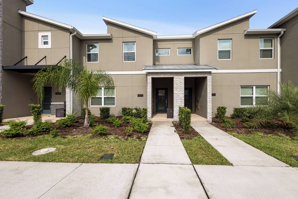 Experience a charming exterior surrounded by lush landscaping and palm trees that warmly welcomes you. The modern architecture and inviting entryways promise a delightful stay filled with comfort and style.