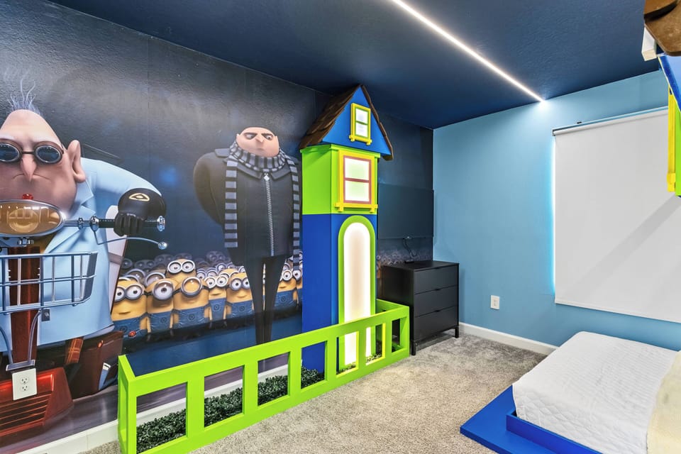Welcome to a whimsical children's room with a vibrant blue wall and beloved characters. The playful green and blue decor, including a charming dollhouse, creates a fun atmosphere for young guests to play and explore comfortably.