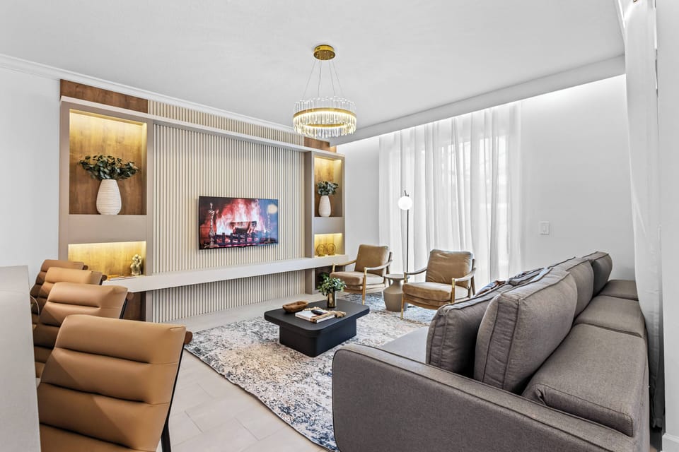 This bright and airy living room boasts a stylish gray sofa and warm leather armchairs, ideal for relaxation. Soft lighting highlights the elegant decor, creating a welcoming space perfect for casual gatherings with friends.