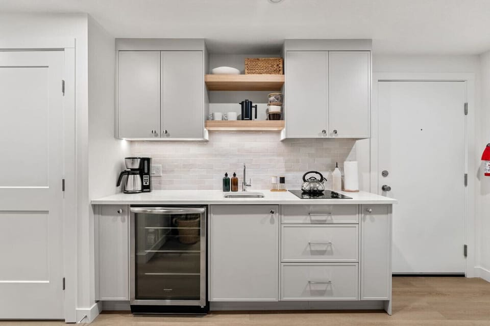 Kitchenette with a mini fridge, drip coffee maker and a stove top.