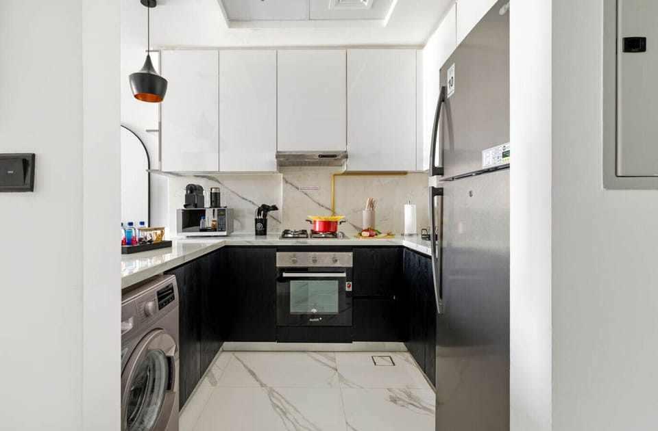 Fully equipped kitchen with oven, fridge, washer, microwave, and coffee machine.