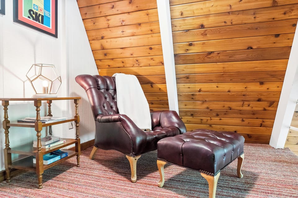 Unplug in the Serene and Comfortable  Loft Area. This vintage leather chair and ottoman set beneath the A-Frame's warm wood ceiling is the perfect place to curl up with a book or enjoy a quiet moment with a hot drink.  