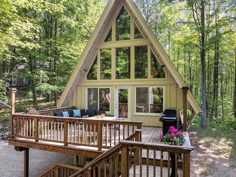 A charming A-frame cabin nestled in the woods, with a spacious deck for outdoor dining, grilling, and soaking in the forest views.