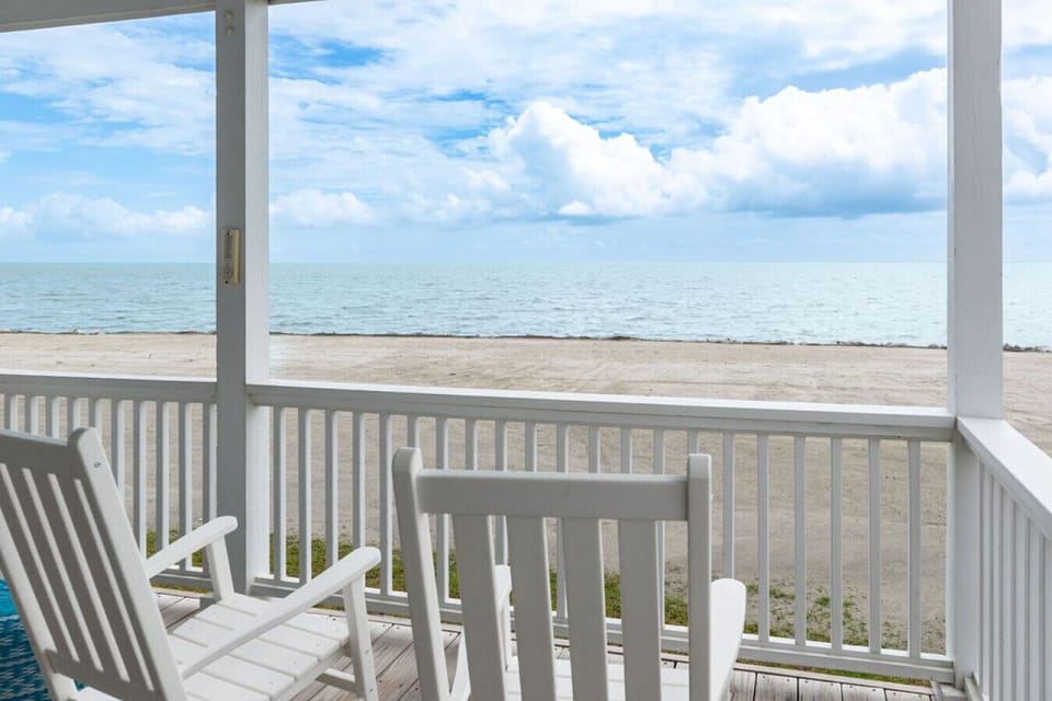 Outdoor seating area with rocking chairs and shoreline scenery