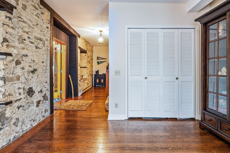 Admire the blend of history and charm in this hallway lined with exposed stone, hardwood floors, and antique-style accents. 🏰🕯️🌲