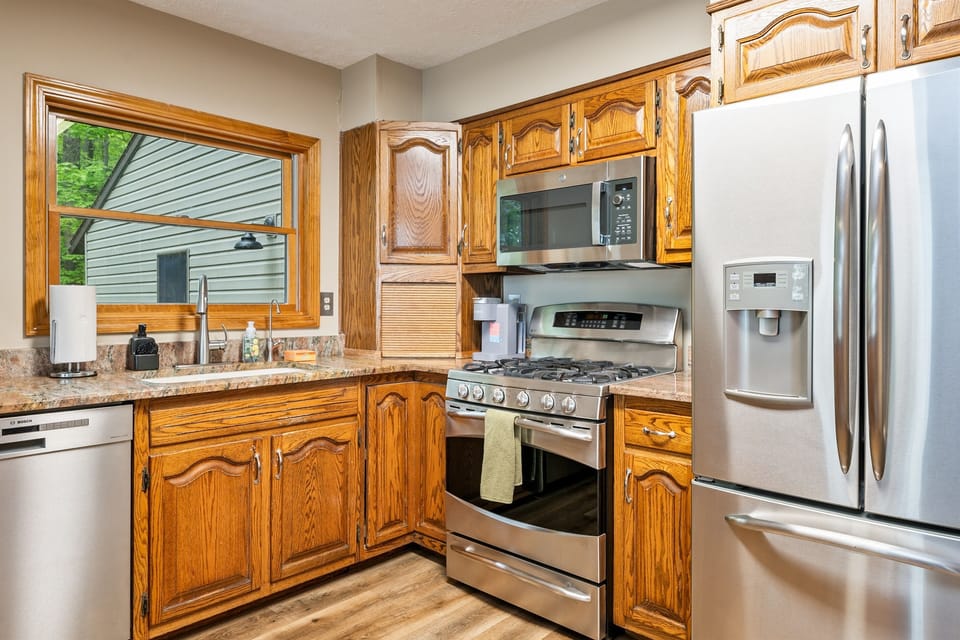 Enjoy forest views while prepping meals in this fully equipped kitchen featuring rich wood cabinetry and modern finishes. 🌲🍴
