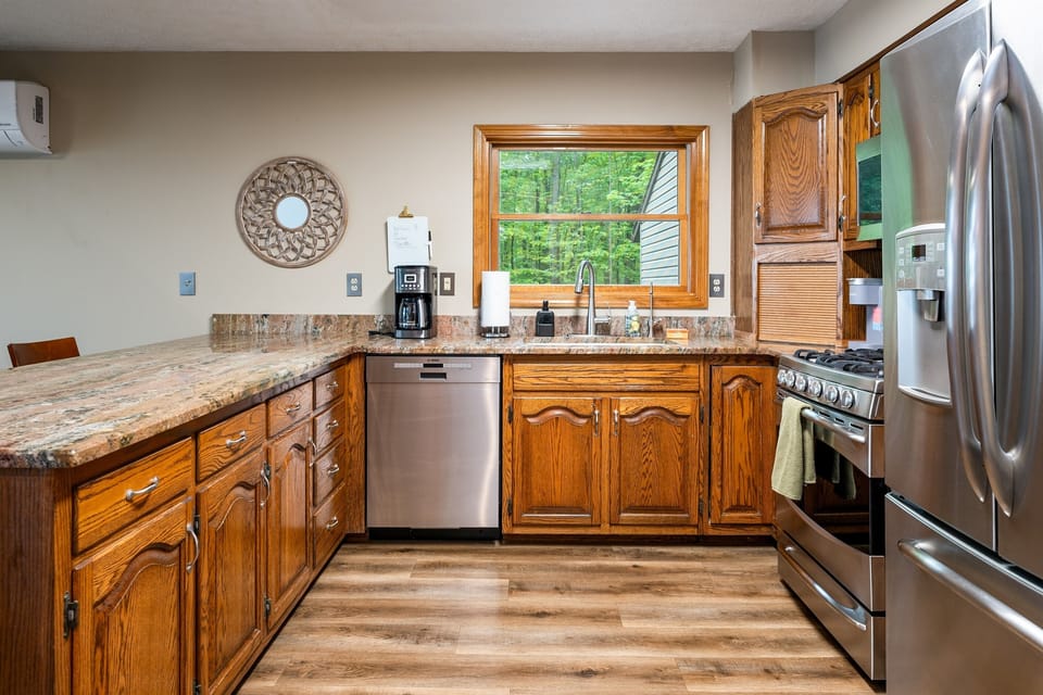 Enjoy forest views while prepping meals in this fully equipped kitchen featuring rich wood cabinetry and modern finishes. 🌲🍴