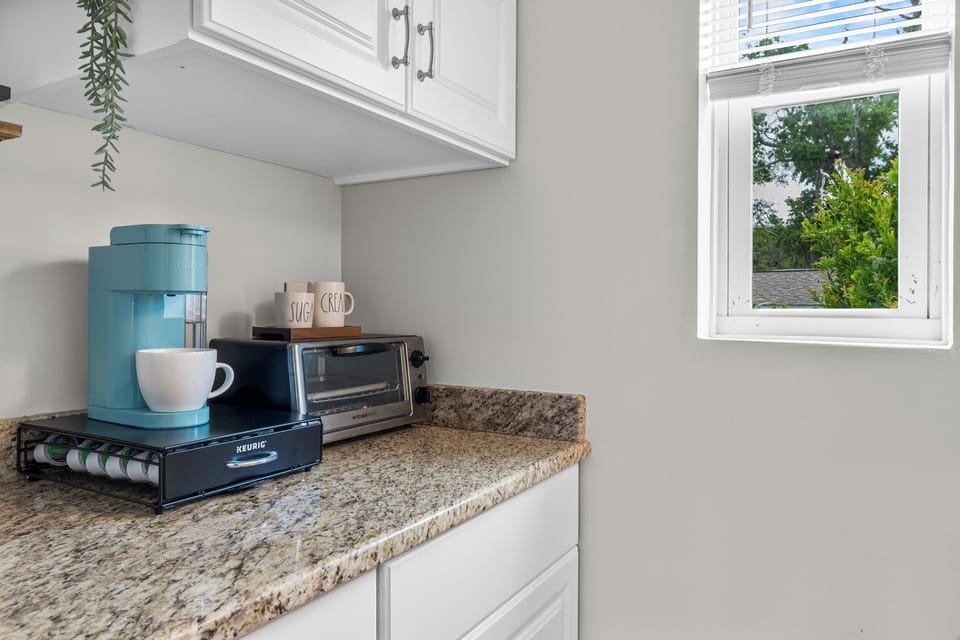 Prepare simple meals in the well‑equipped kitchenette featuring a cooktop, microwave, small fridge, and a Keurig + Carafe Coffee Maker.
