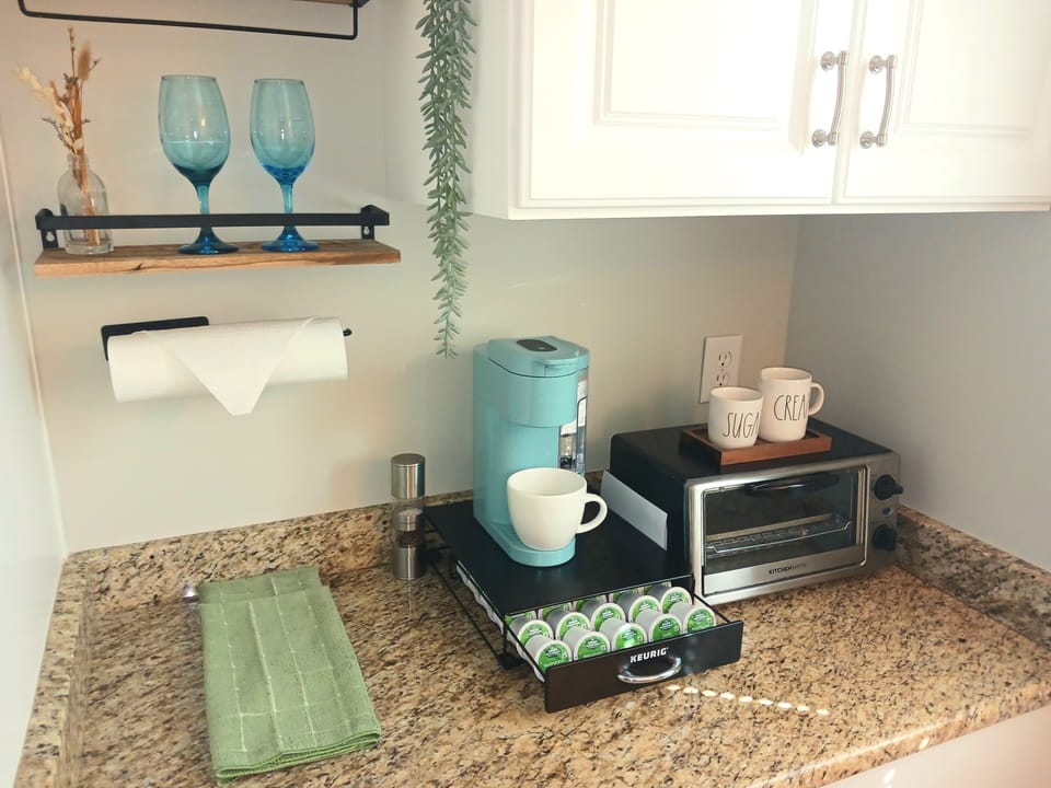 Prepare simple meals in the well‑equipped kitchenette featuring a cooktop, microwave, small fridge, and a Keurig + Carafe Coffee Maker.