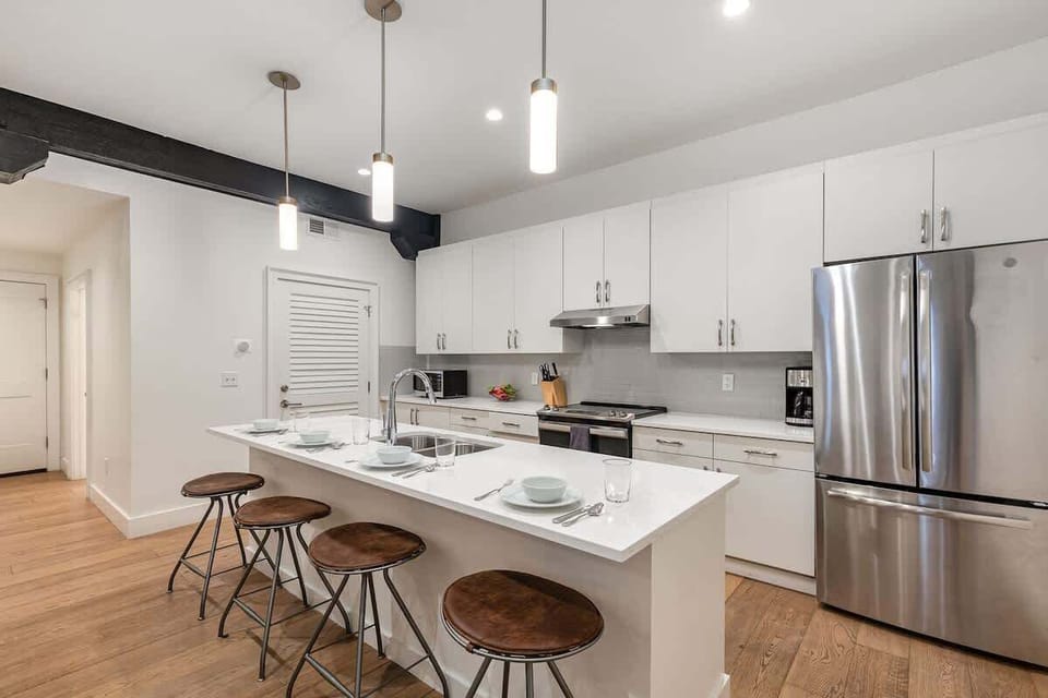 Kitchen with stainless steel appliances, white cabinetry and countertops, a central island, and breakfast bar seating for 4.