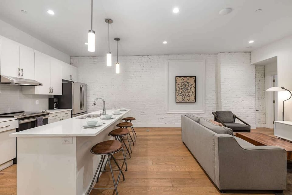 Living room with open-concept design featuring a white brick wall, Smart TV, and comfy sleeper sofa—ideal for lounging or accommodating extra guests.