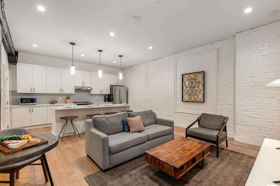 Living room with open-concept design featuring a white brick wall, Smart TV, and comfy sleeper sofa—ideal for lounging or accommodating extra guests.