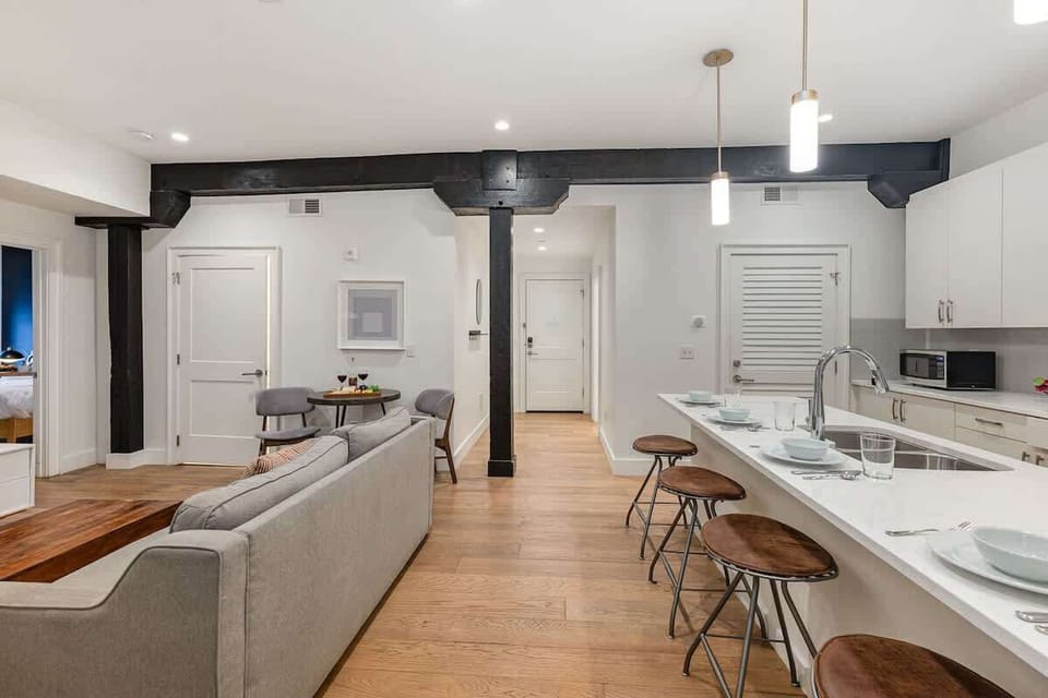 Living room with open-concept design featuring a white brick wall, Smart TV, and comfy sleeper sofa—ideal for lounging or accommodating extra guests.