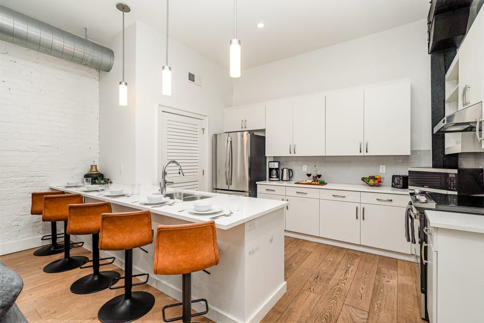 Unit 1: Fully equipped kitchen featuring stainless steel appliances, open counter space, and bar seating for 5 guests.