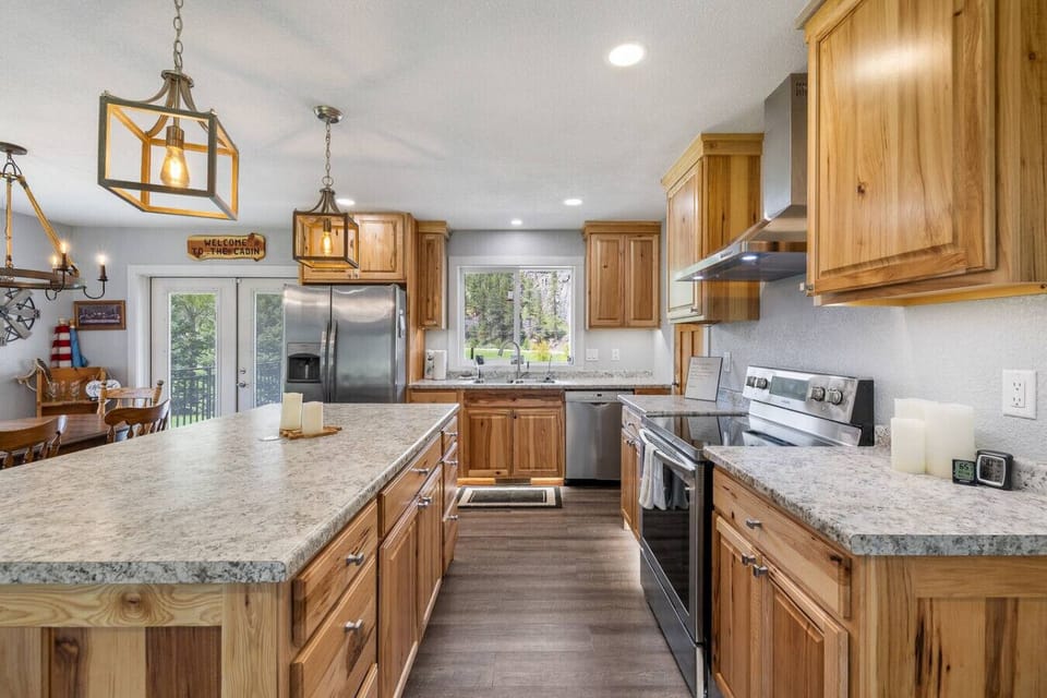 Warm wood and sleek stainless steel meet in this fully stocked kitchen with granite countertops, dishwasher, double-door fridge, stove, oven, and crockpot—where comfort meets function.
