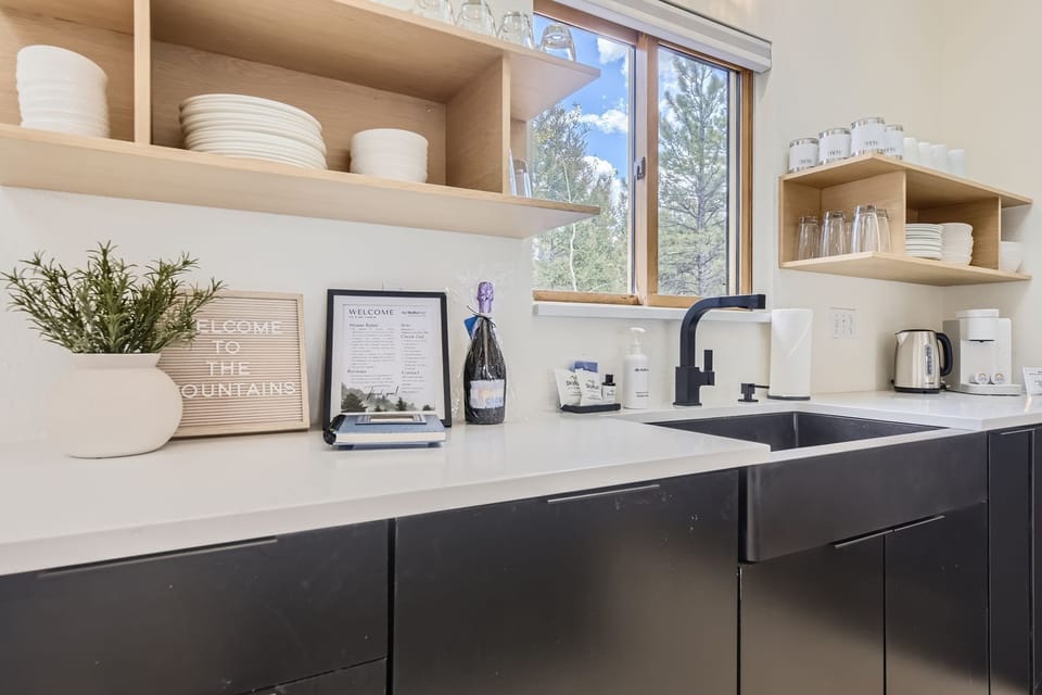 Your modern kitchen awaits with sleek countertops, open shelving, and thoughtful welcome touches including local wine and amenities.