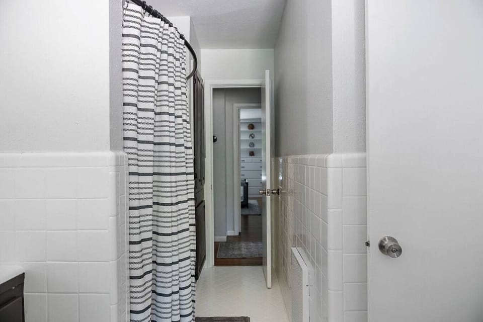 Fresh and bright bathroom with a stylish striped shower curtain, clean tile walls, and all the essentials for a refreshing start or relaxing end to your day.