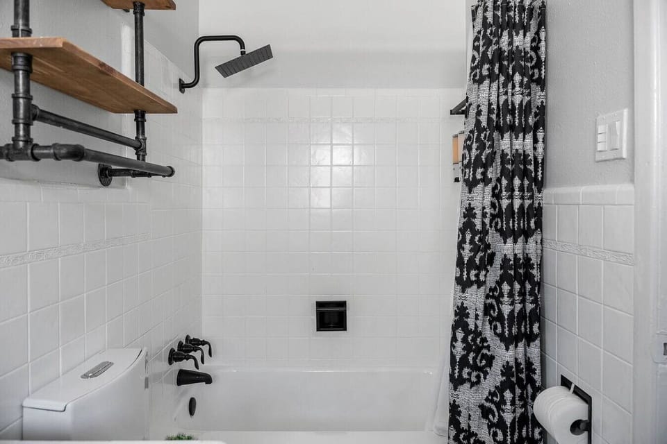 Stylish bathroom with a rainfall showerhead, modern black fixtures, and thoughtful shelving for your essentials
