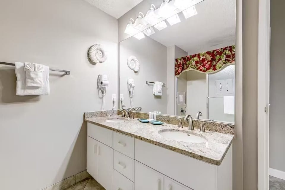 Freshen up in your spacious bathroom featuring dual vanities, granite countertops, and thoughtful coastal touches that make morning routines feel luxurious.