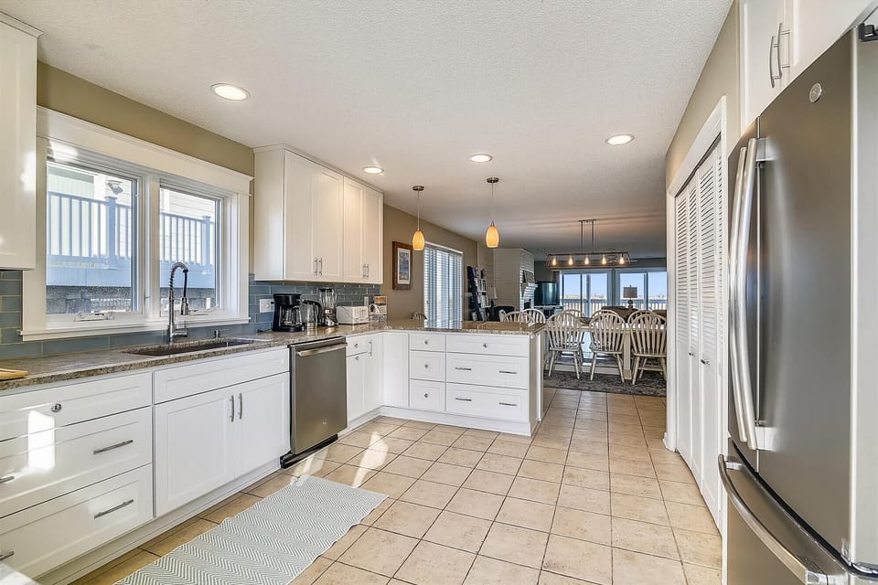 Your fully equipped kitchen gleams with stainless steel appliances and granite countertops, ready for creating vacation feasts or morning coffee while sunlight streams through windows.