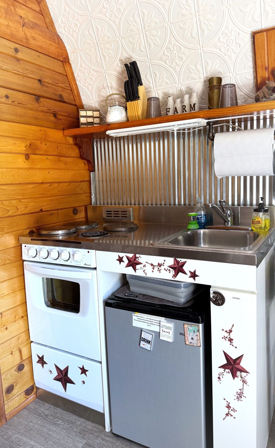 Small kitchenette with an oven, stove, small refrigerator, and keurig.