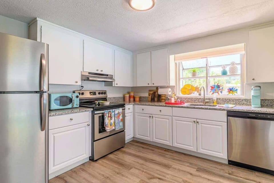 Kitchen features stainless steel appliances, granite countertops, white cabinetry, and a cozy dining window. It’s fully equipped with a microwave, stove, dishwasher, and essentials for a comfortable cooking experience.