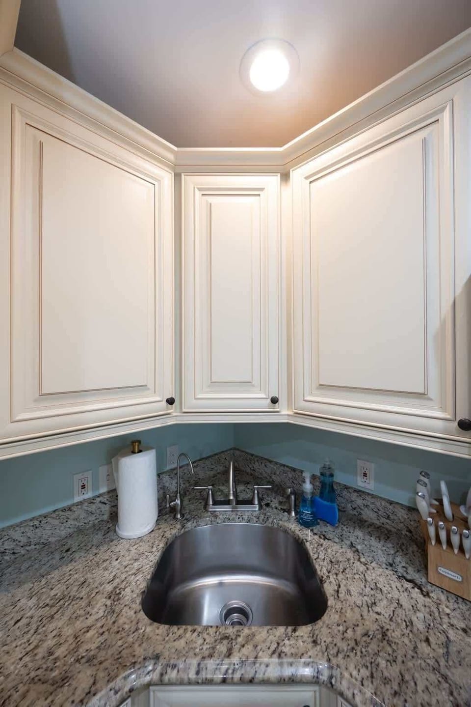 Kitchen with stainless steel appliances, granite countertops, and cream cabinetry. A large peninsula with bar seating and pendant lighting connects to the open living area, blending function and comfort with beachy decor accents.