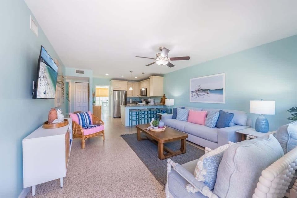 A bright, coastal-themed living room with pastel blue walls and cozy seating.