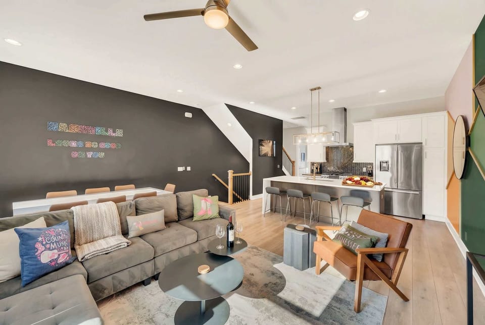 Open-concept living and kitchen with a sectional sofa, dining table for 12, and an island bar where the cook stays in the conversation