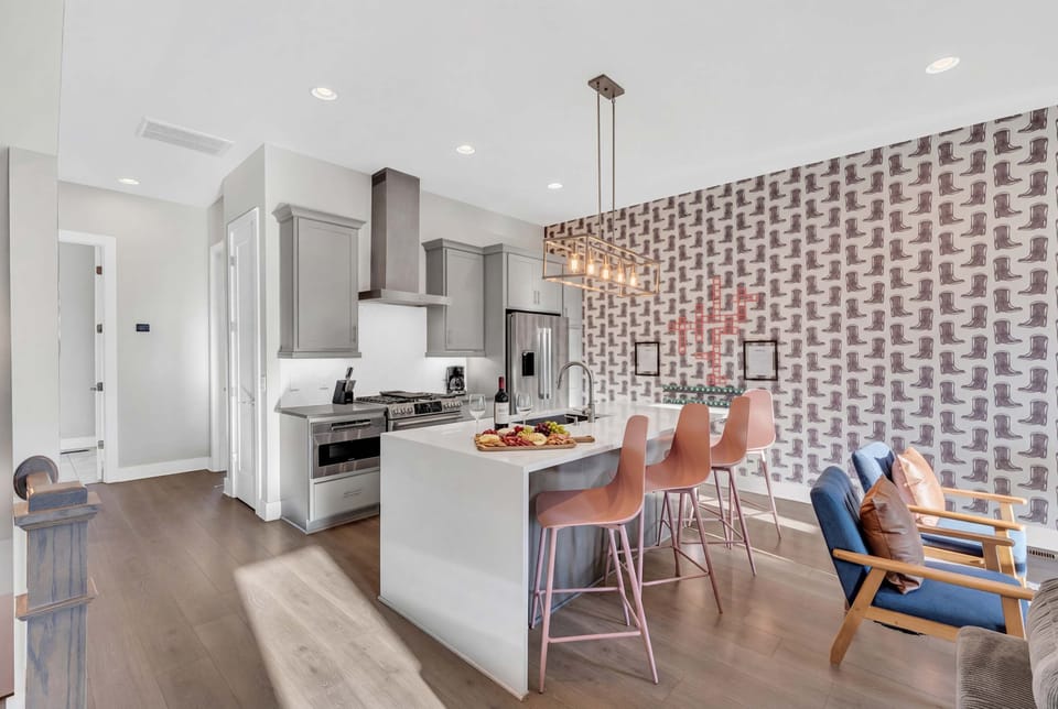 Cowboy boot wallpaper frames the oversized kitchen island with bar stools, stainless steel appliances, and a gathering spot built for group dinners