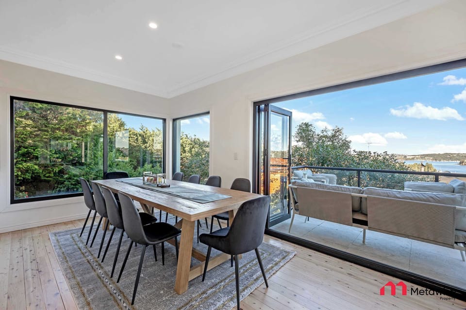Dining area with large table and sliding doors opening to the balcony with water views.