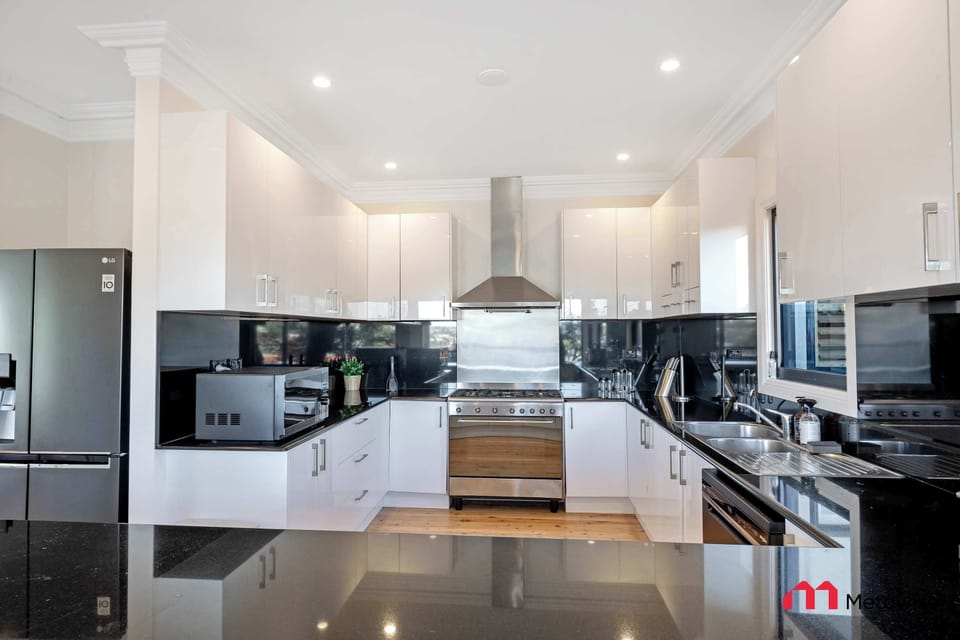 Contemporary kitchen with island bench, stone benchtops, stainless steel appliances, and ample storage.