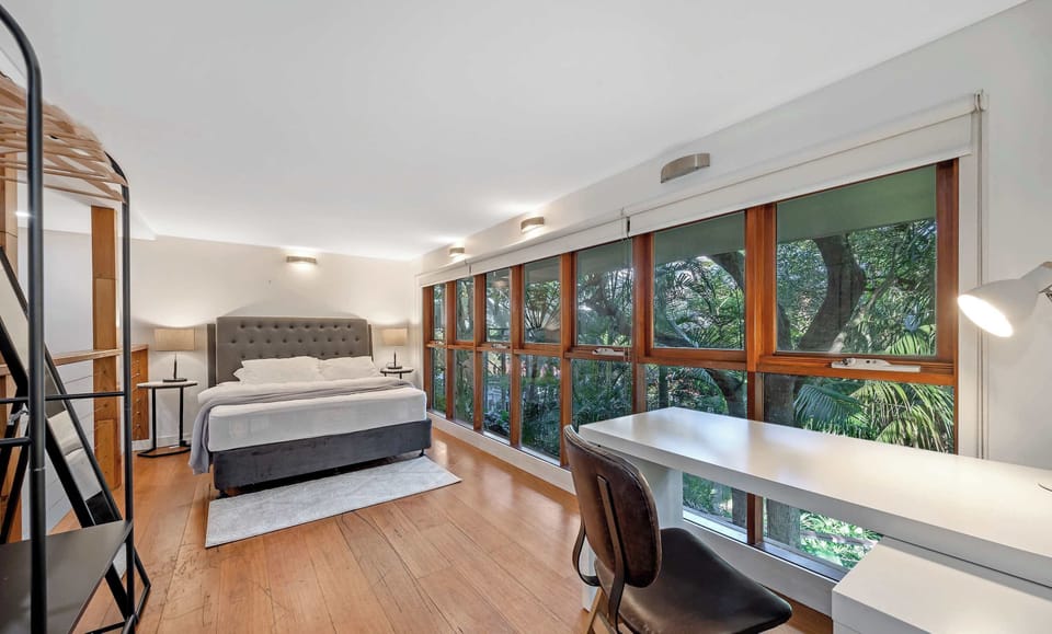Study/workspace with long desk, shelving, and window views.