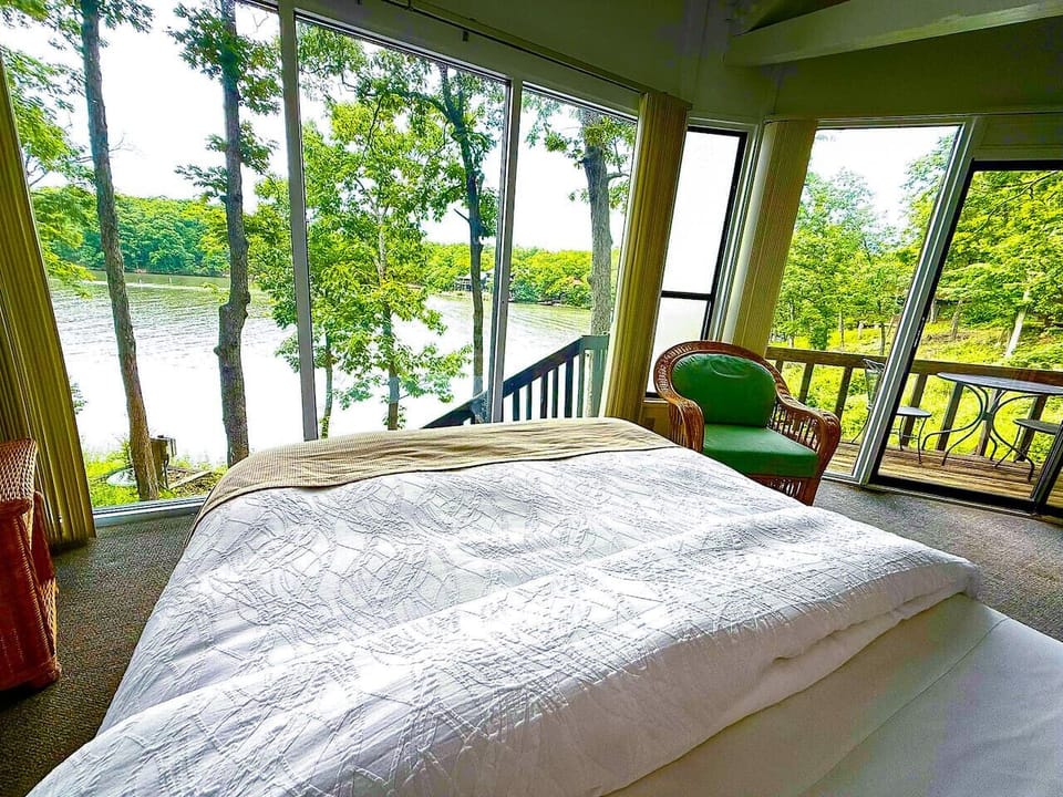 Retreat to a peaceful bedroom with large windows offering a serene view of the surrounding trees, providing a private and tranquil atmosphere.