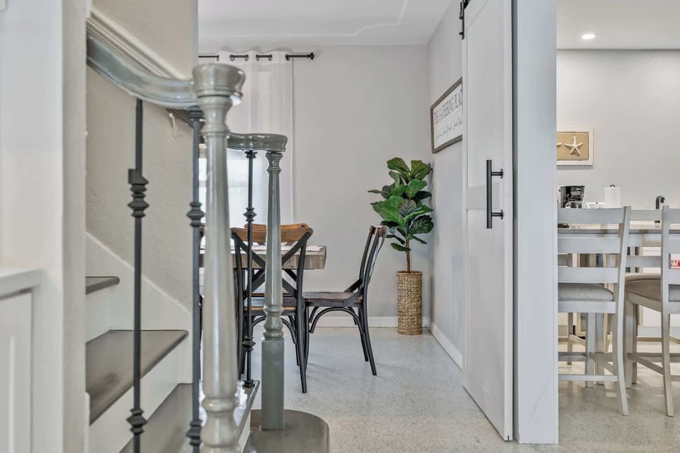 View of the dining area and kitchen with a modern staircase in the foreground