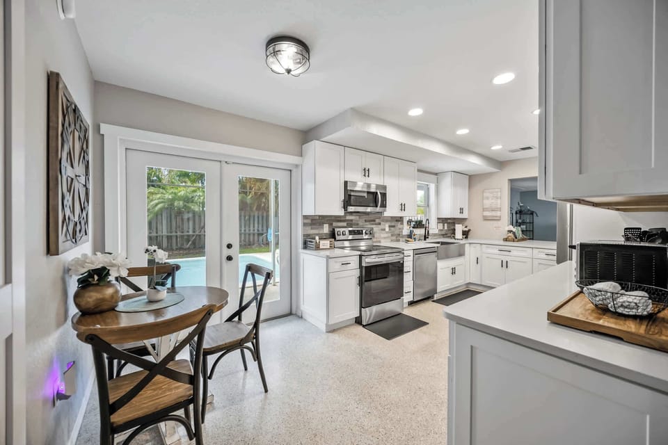 Modern kitchen with stainless steel appliances and a view of the backyard pool through glass doors.