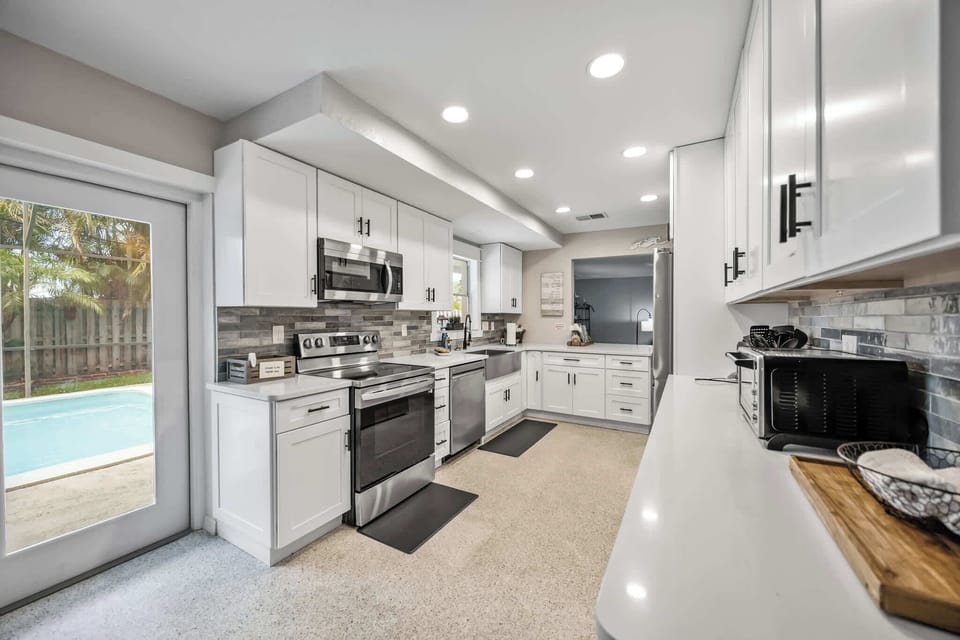 Modern kitchen with stainless steel appliances and a view of the pool area.