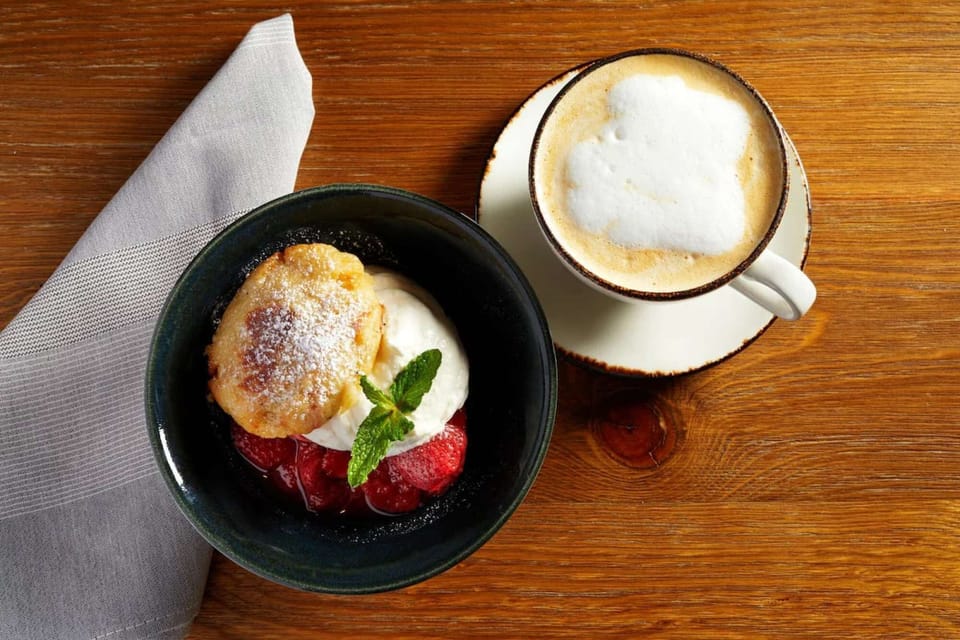Dessert and coffee served on a wooden table with a napkin