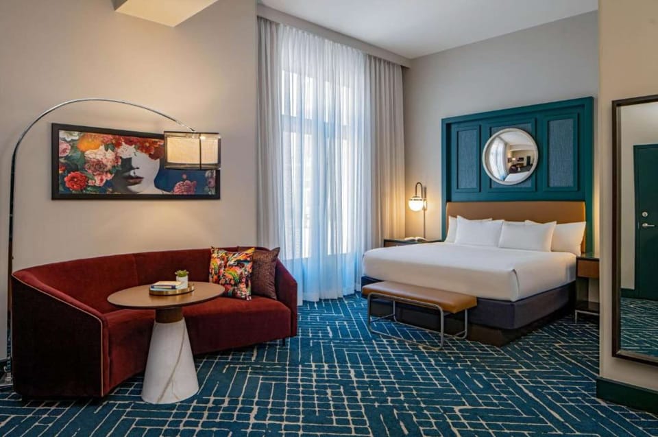 Spacious  bedroom with king bed and red sofa.