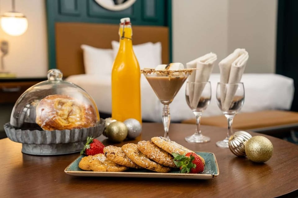 Cookies, pastry, and drinks on table near hotel bed