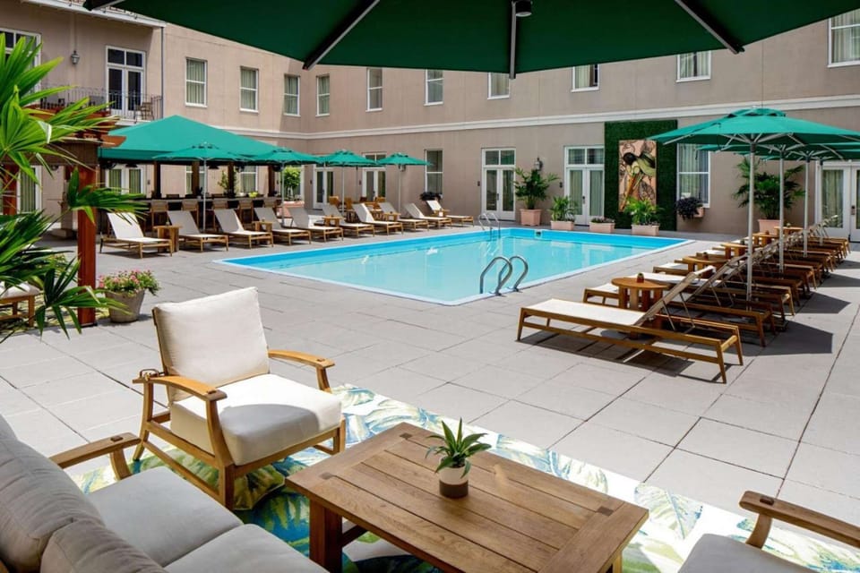 Modern poolside seating with green umbrellas and soft chairs