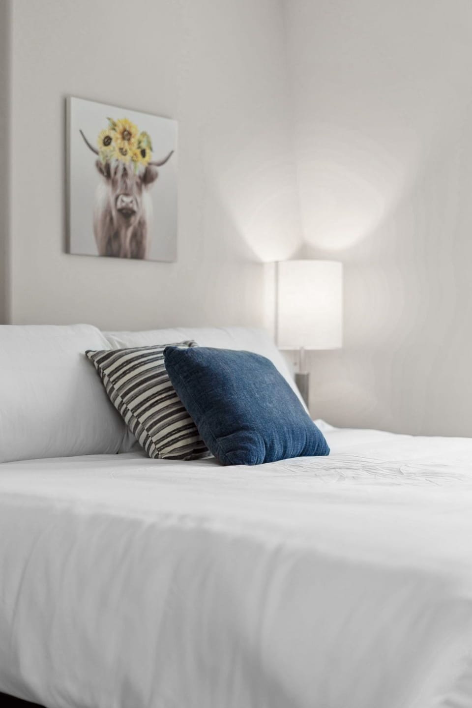 Drift off to sleep in your peaceful bedroom with crisp white linens and charming highland cow artwork watching over you.