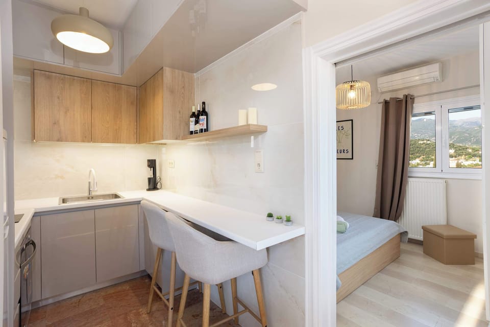 Bright and open layout featuring a sleek kitchenette, cozy breakfast bar, and a peek into the peaceful bedroom beyond.