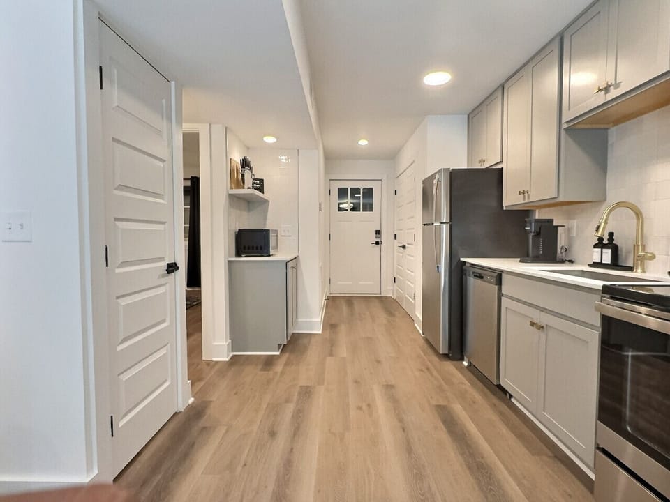 Modern kitchen with sleek stainless steel appliances and neatly arranged utensils, perfect for effortless cooking during your short-term rental stay.