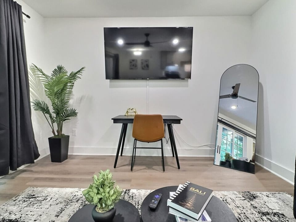 Bright and airy living area in this furnished apartment with comfortable seating, a TV, and a workspace, sleek window with city views, perfect for relaxing or staying productive.