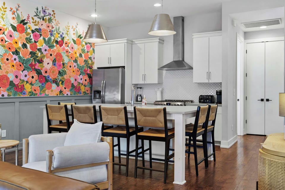 Bright and modern fully equipped kitchen featuring stainless steel appliances, a spacious island with bar seating, ample counter space, and an open-concept layout perfect for cooking and gathering.