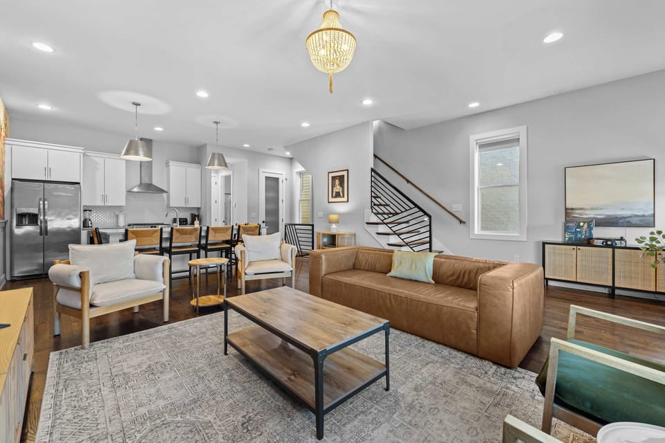 Located on the 2nd floor, the bright and stylish open-concept living room featuring comfortable seating, a large Smart TV, a colorful floral accent wall, and a vintage record player – perfect for relaxing and spending time together.