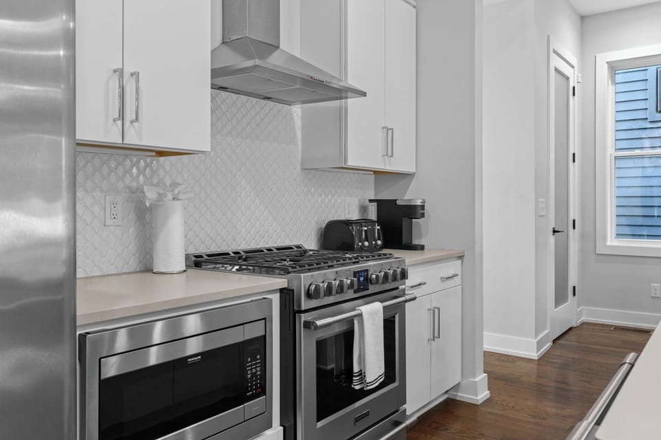 Bright and modern fully equipped kitchen featuring stainless steel appliances, a spacious island with bar seating, ample counter space, and an open-concept layout perfect for cooking and gathering.