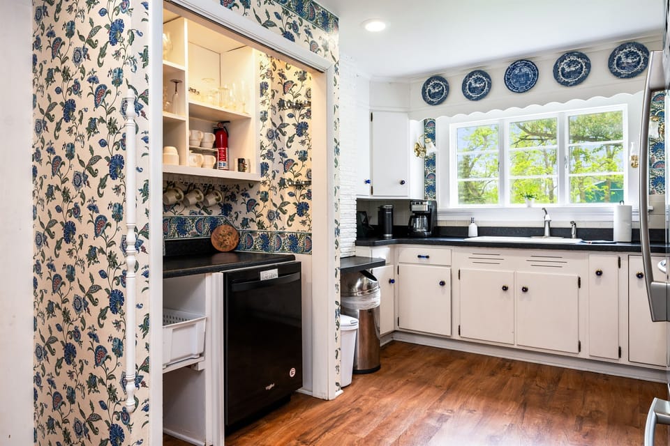 Charming vintage kitchen with modern stainless steel appliances, classic blue accents, and a scenic view above the sink 🌿🍽️💙