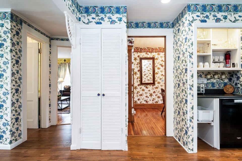 Warm, character-filled hallway with floral wallpaper and peekaboo views into cozy sitting and dining rooms 🌸🚪✨